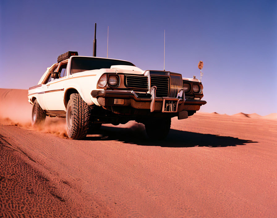 Vintage White Car with Extra Lights and Antennas Racing Across Sandy Desert Dunes