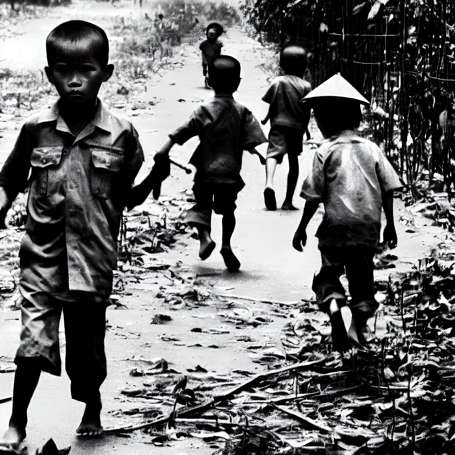 Black and white photo of five children in traditional and modern clothing walking on a path