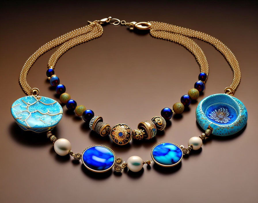 Gold chain necklace with large blue pendants and accent beads on brown surface