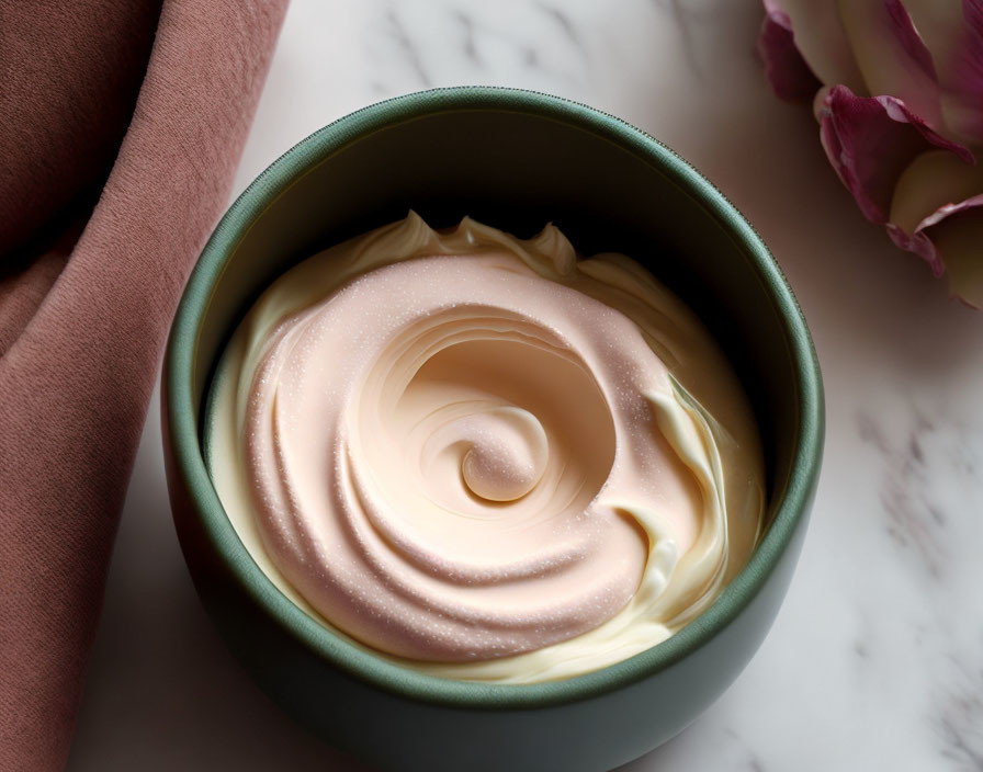 Soft Pink and White Body Cream in Green Bowl with Blush Textile and Pink Flower on Marble Surface