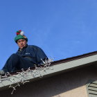 Child in festive hat on snowy rooftop gazes at village lights