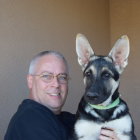 Surreal portrait: man with silver hair and glasses next to large dog with colorful eye patterns