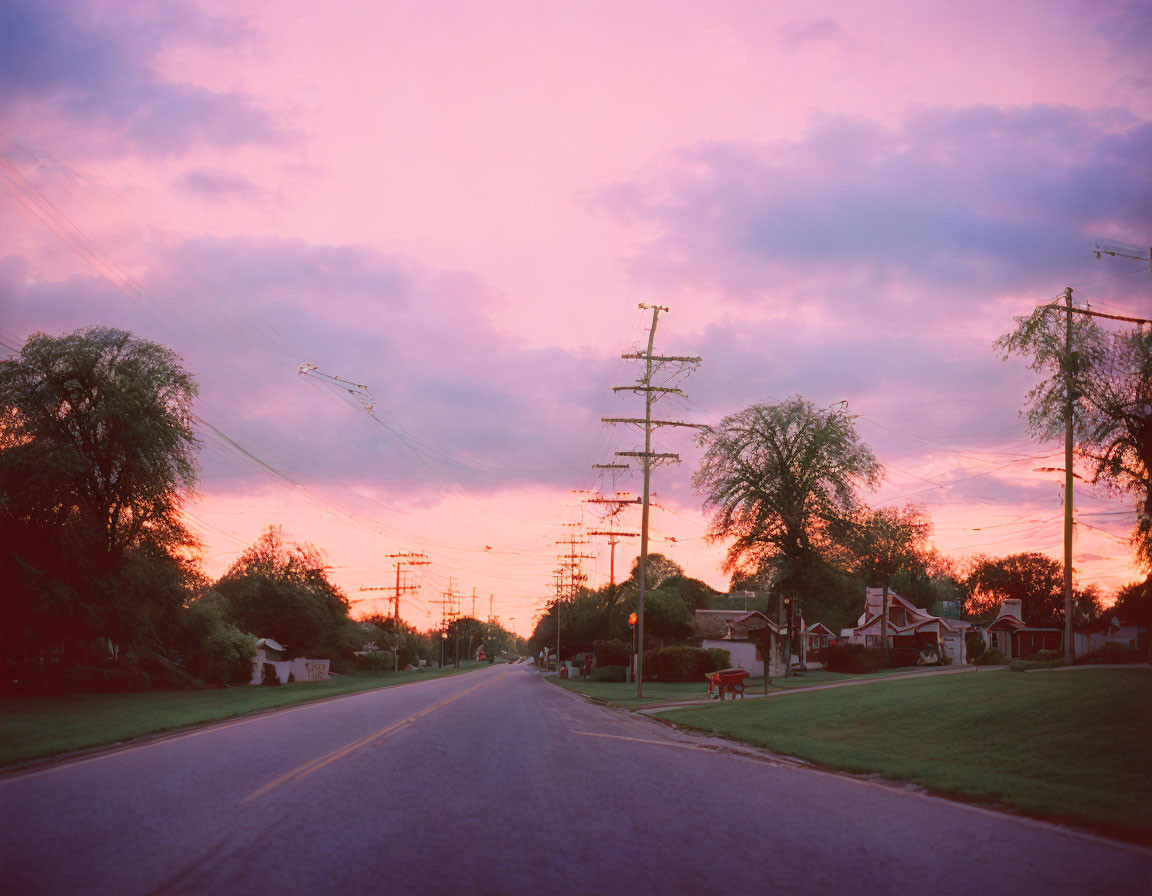 Tranquil suburban street at sunset with vibrant pink and orange skies