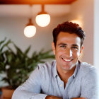 Smiling man in glasses indoors with plants and lights