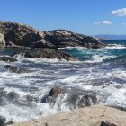 Layered rock formations on rocky coastline by turquoise sea