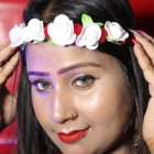 Woman with floral headband and sparkly makeup in front of red bokeh lights