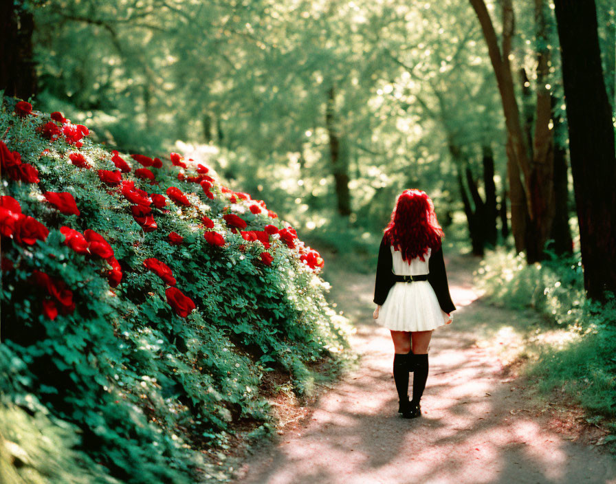 Red-haired woman strolls on forest path with vibrant flowers and sunlight