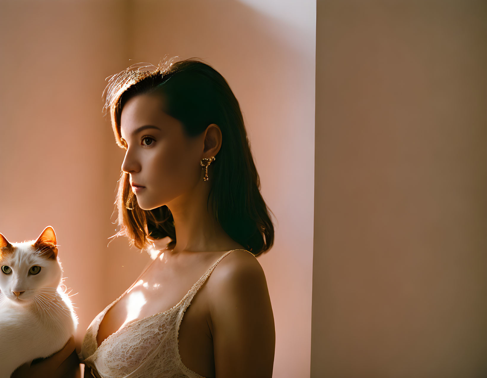 Woman in lace top holding white cat in soft light