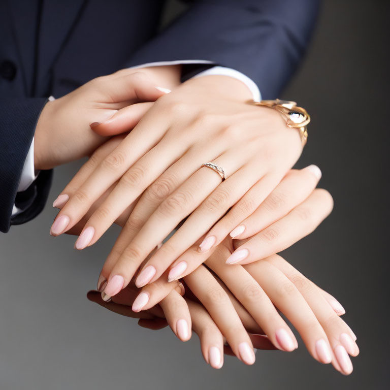 Elegant pink manicured hands with diamond ring and wristwatch on dark background