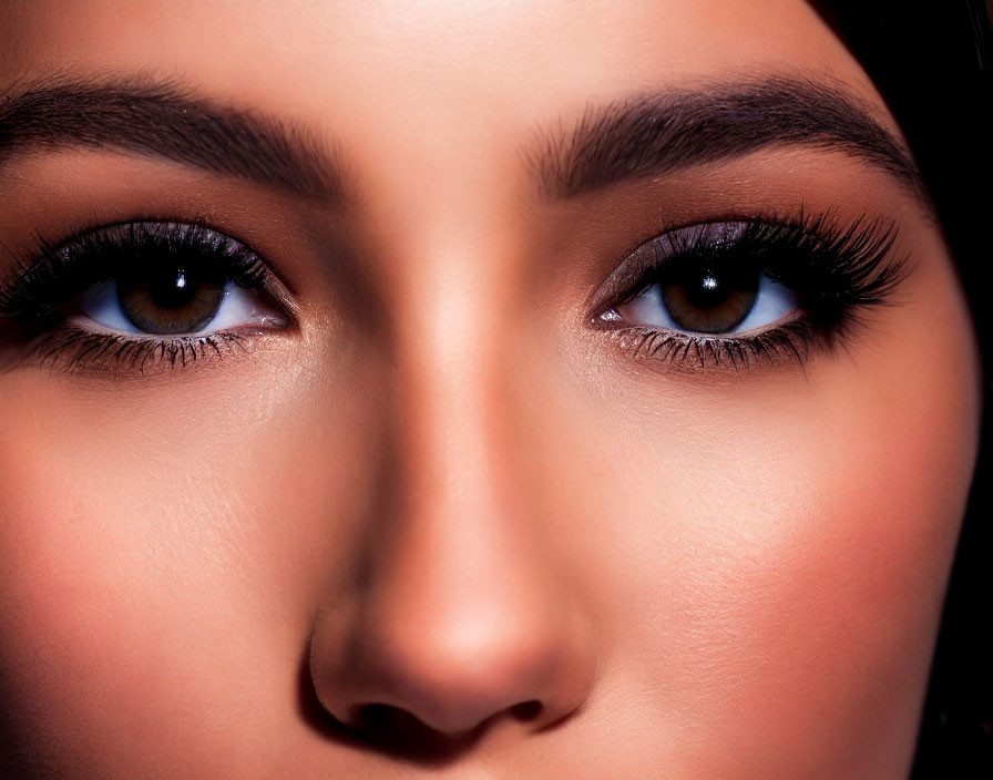 Brown-eyed woman with full lashes and shaped eyebrows up close.