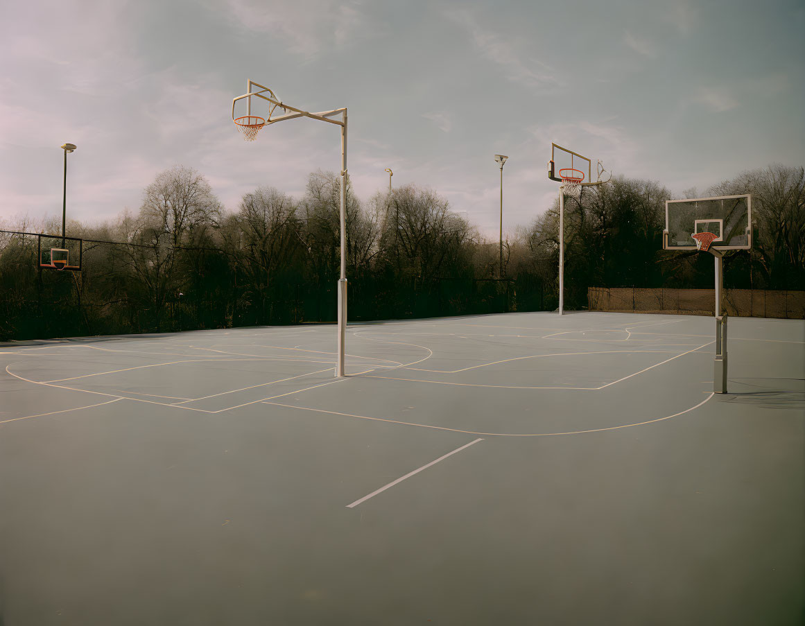 Outdoor Basketball Court with Multiple Hoops and Painted Lines on Cloudy Day