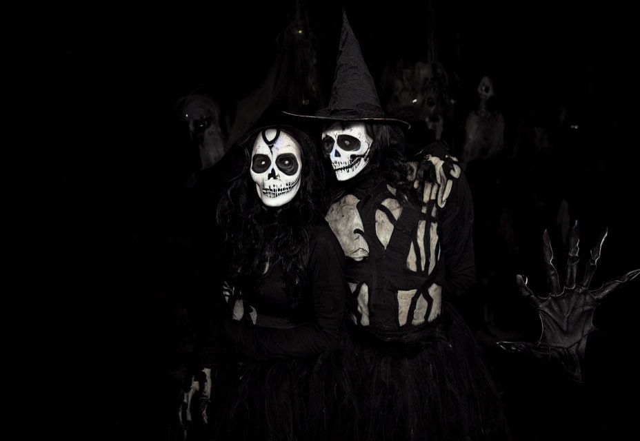 Pair of individuals in dark, skeletal costumes with face paint, one waving.