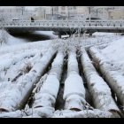 Snow-covered winter landscape with calm river and bare trees