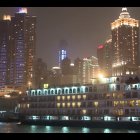 Futuristic city skyline at sunset with illuminated skyscrapers reflected in calm water