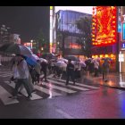 Colorful neon-lit street scene with wet pavement and parked cars