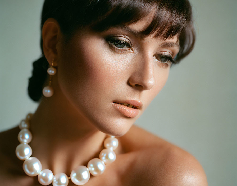 Woman wearing pearl necklace with subtle makeup in pensive pose