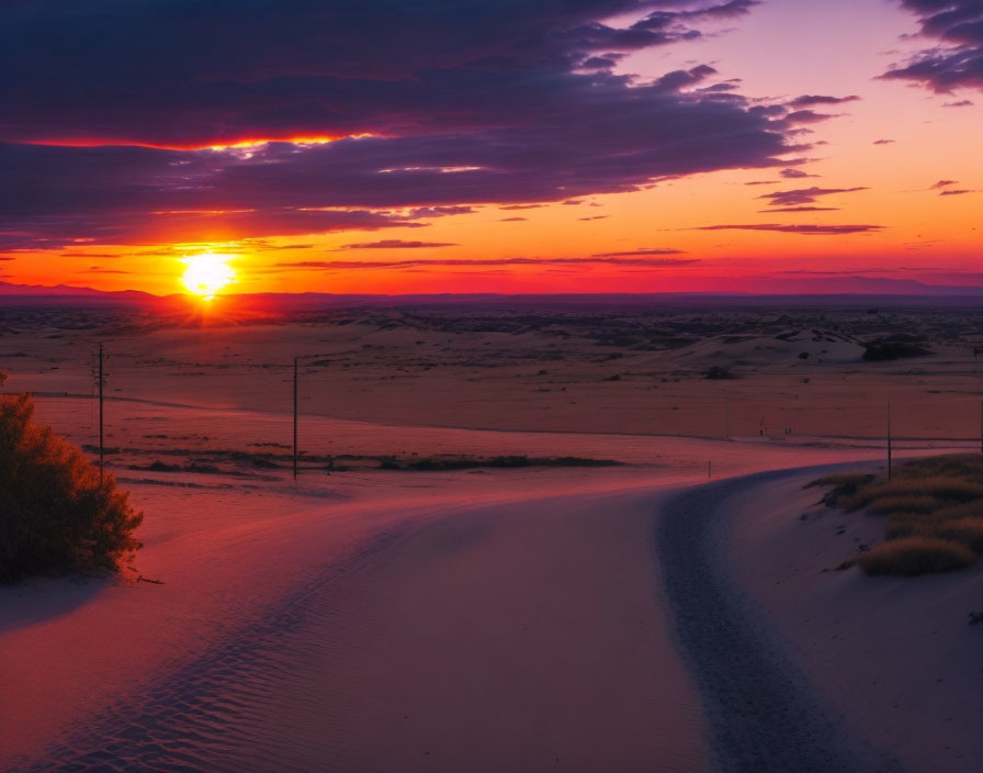 Vibrant purple and orange desert sunset with warm glow on sandy terrain