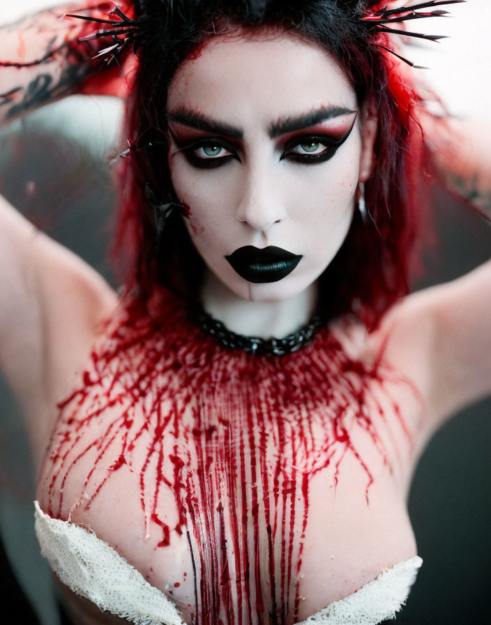 Person with black and red makeup and blood splatter, showcasing a gothic, horror-inspired look