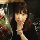 Woman with radiant skin and lustrous brown hair adorned with flowers and tears reflection.