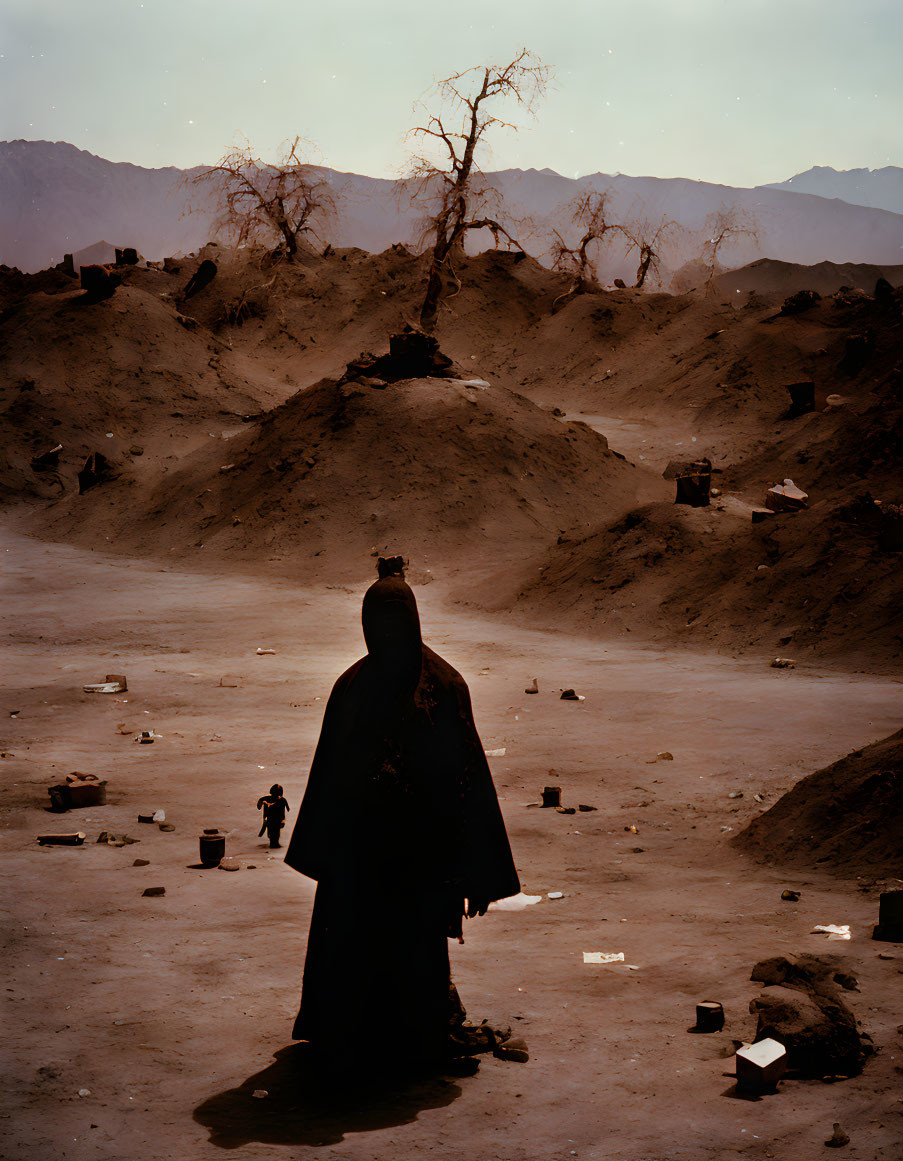 Mysterious figure in dark cloak in desolate landscape