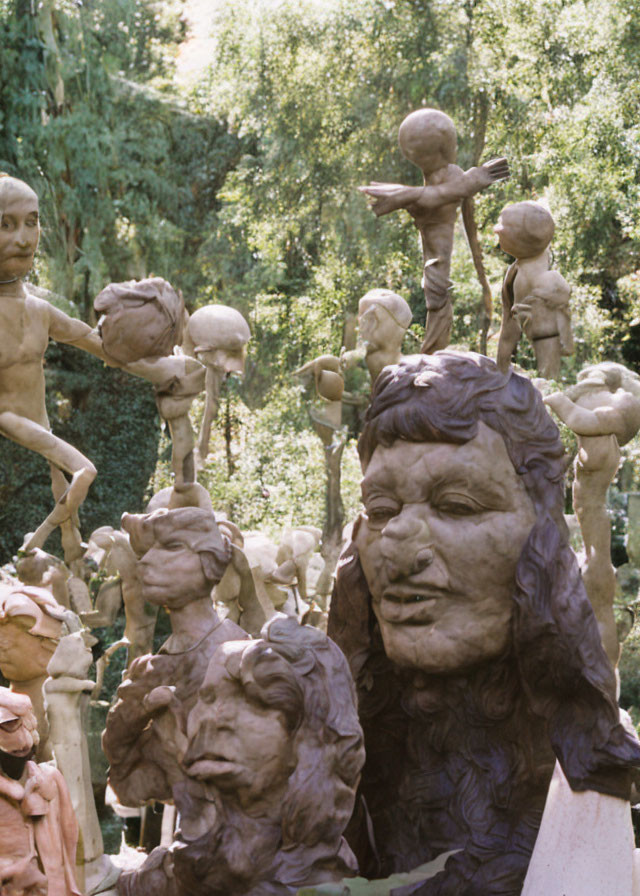 Large Head Sculpture with Acrobatic Figures in Green Foliage