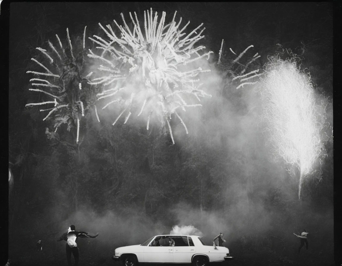 Monochrome photo: person on car, arms outstretched, two others on ground, all with