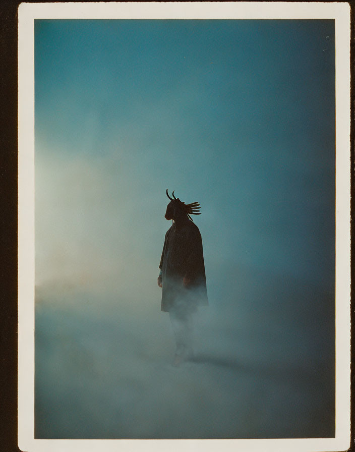 Mystical figure in horned headdress amid fog at twilight