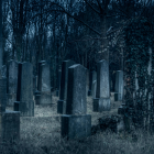 Ghostly Figure in White by Tombstone in Moonlit Cemetery