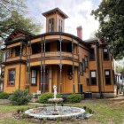 Victorian-style house with ornate woodwork, tower, verandas, and landscaped garden