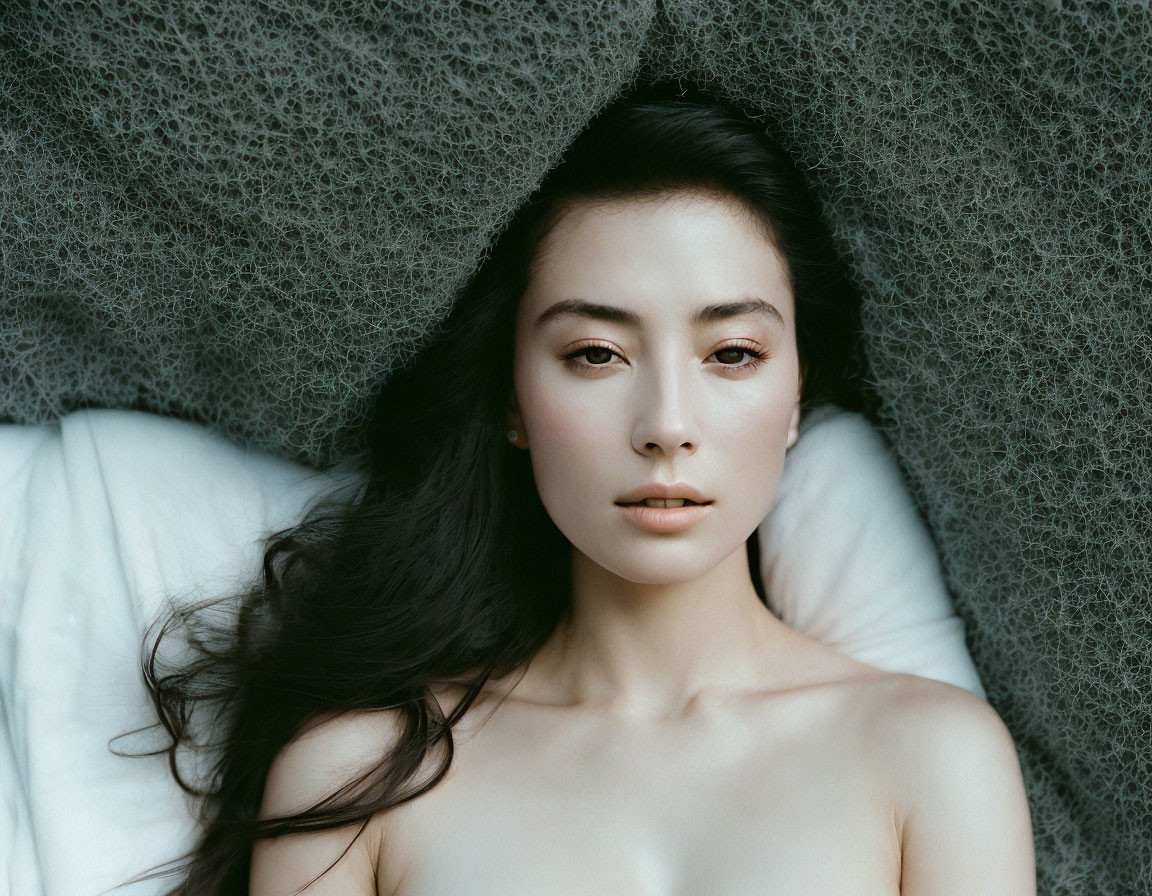 Dark-haired woman lying down with fabric draped over head