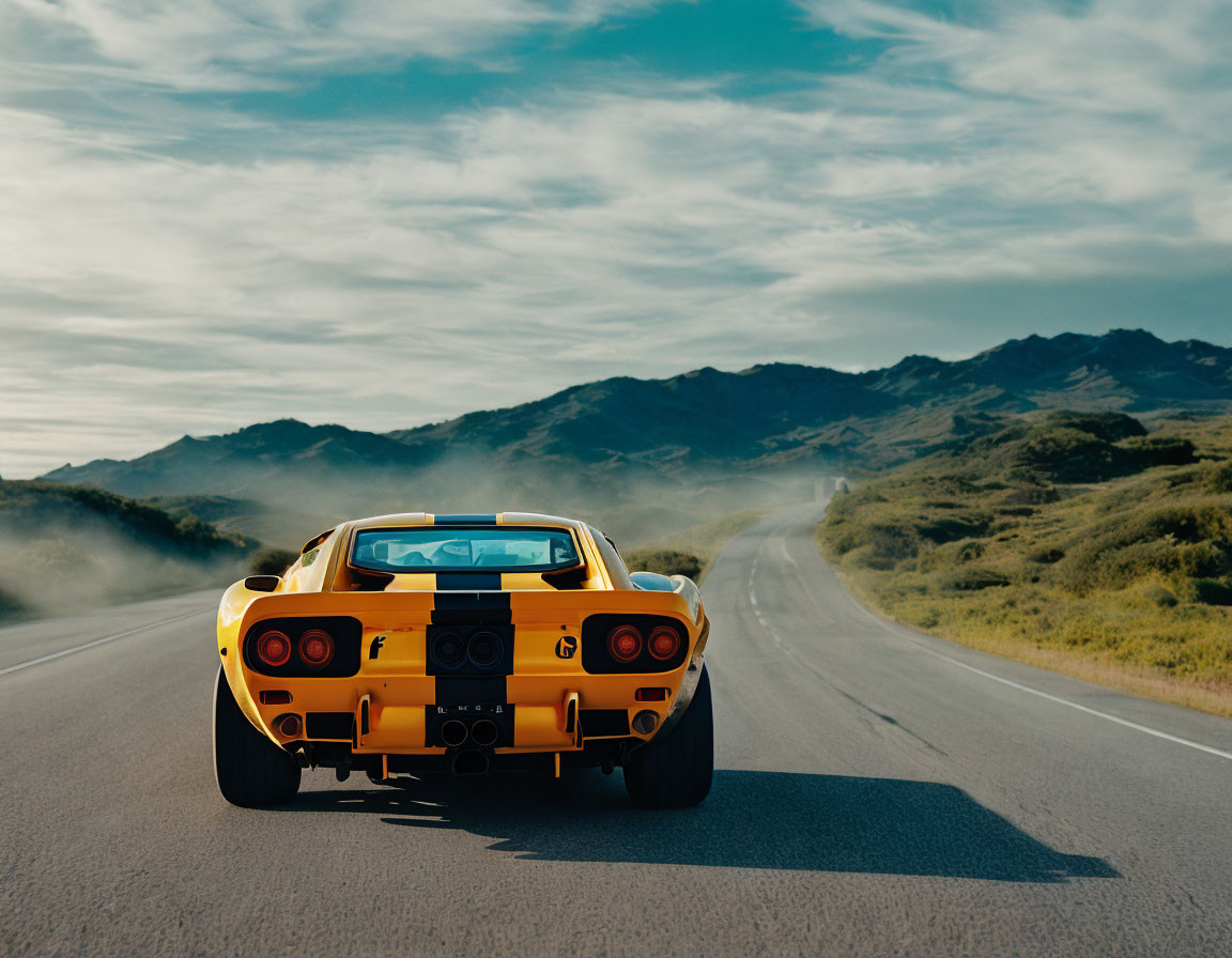 Yellow sports car driving on open road with mountains and clear blue sky