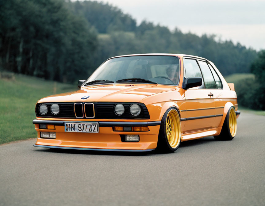 Vintage Orange BMW with Yellow Wheels on Asphalt Road