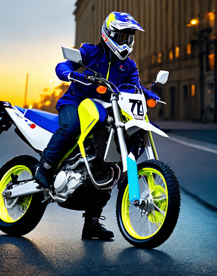 Rider in blue and white gear on white dirt bike with yellow rims in urban street at dusk