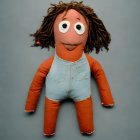 Red and white painted doll with curly brown hair on grey background