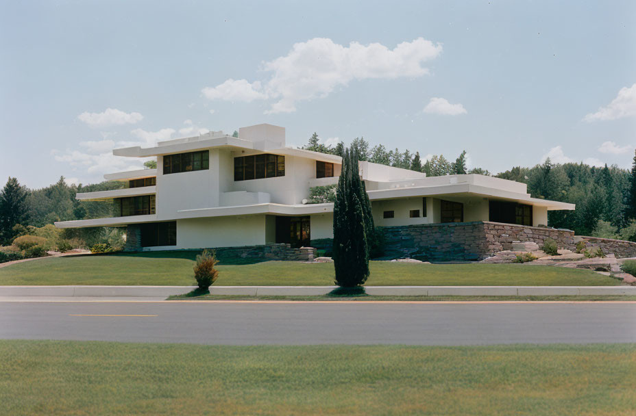 Contemporary white two-story house with flat roofs and large windows in landscaped setting