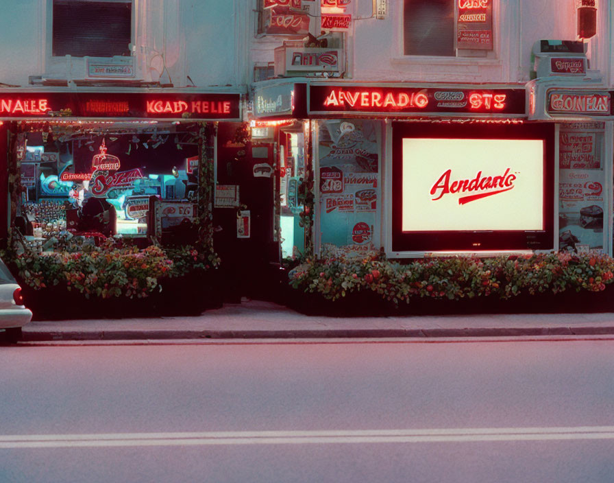 Vibrant neon signs in urban night scene with barbershop, cafe, and flower beds.