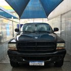 Black Pickup Truck with Blue Tarp on Highway Under Cloudy Sky