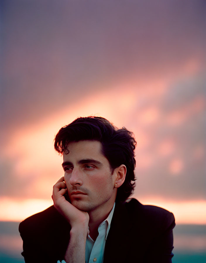 Man with dark hair gazes at sunset sky