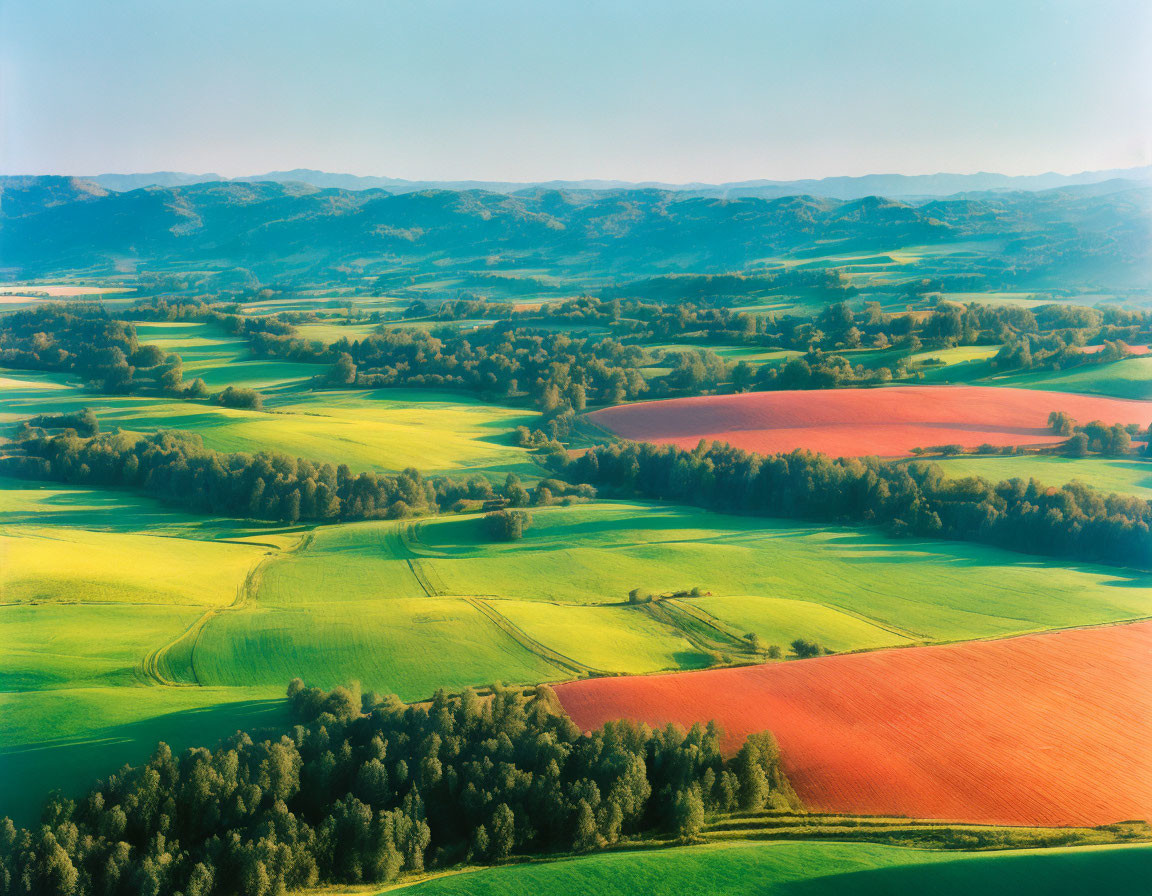 Colorful landscape with rolling fields and hills under clear blue sky