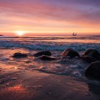 Tranquil sunset seascape with sailboat and vibrant orange skies