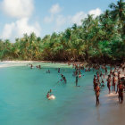 Crowded tropical beach with palm trees and clear blue water