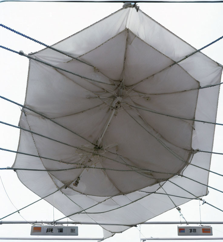 Large White Square Umbrella Surrounded by LED Signs and Cables