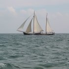 Tall-masted sailing ships on choppy waters at sunset