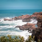 Coastal cliffs facing turbulent sea with rocky outcrops