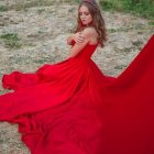 Woman in Red Gown Sitting by Ocean Waves