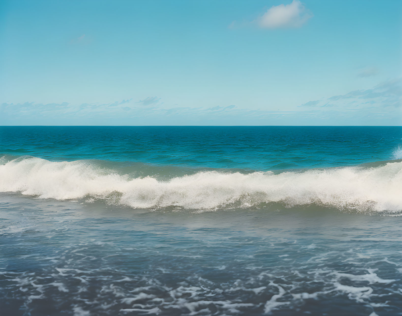 Tranquil blue ocean with gentle waves breaking near the shore