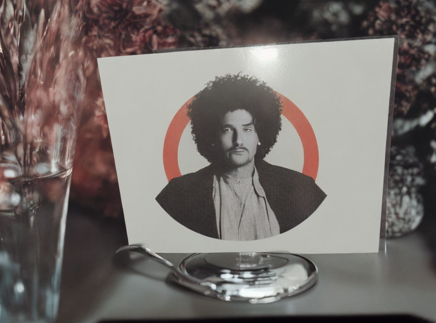 Monochrome portrait with curly hair on red and white target backdrop.