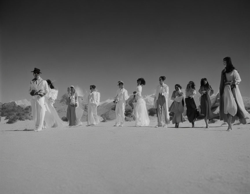 Group of people in white outfits walking in desert under bright sky