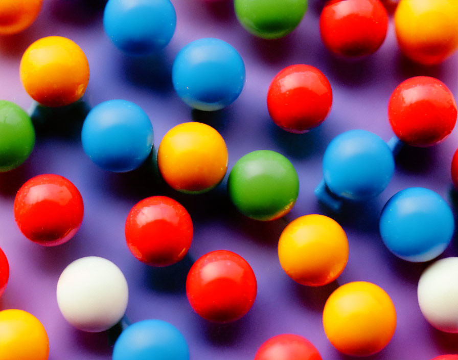 Colorful gumballs on purple surface with shallow depth of field