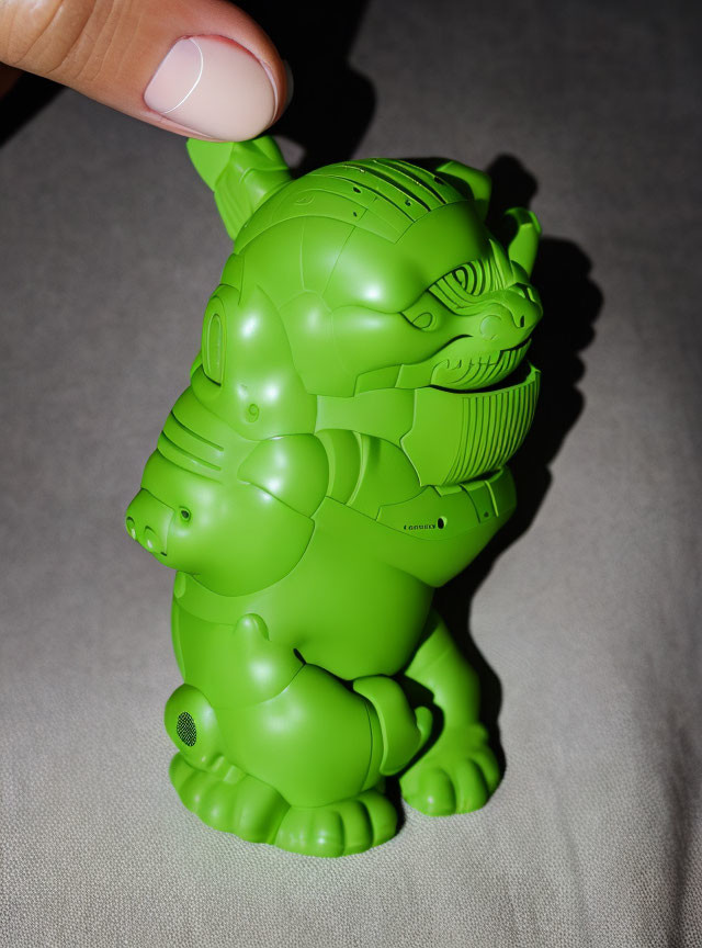 Detailed green stylized figurine with intricate patterns held by a hand